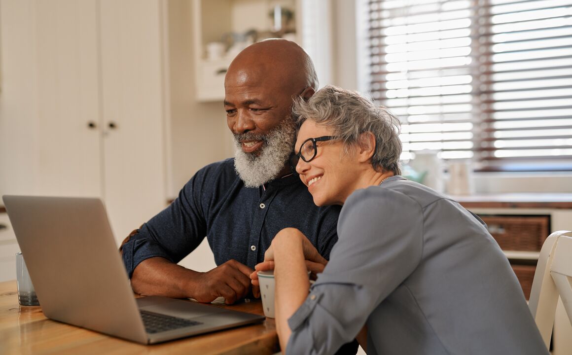 Man and a woman snuggling while looking at laptop