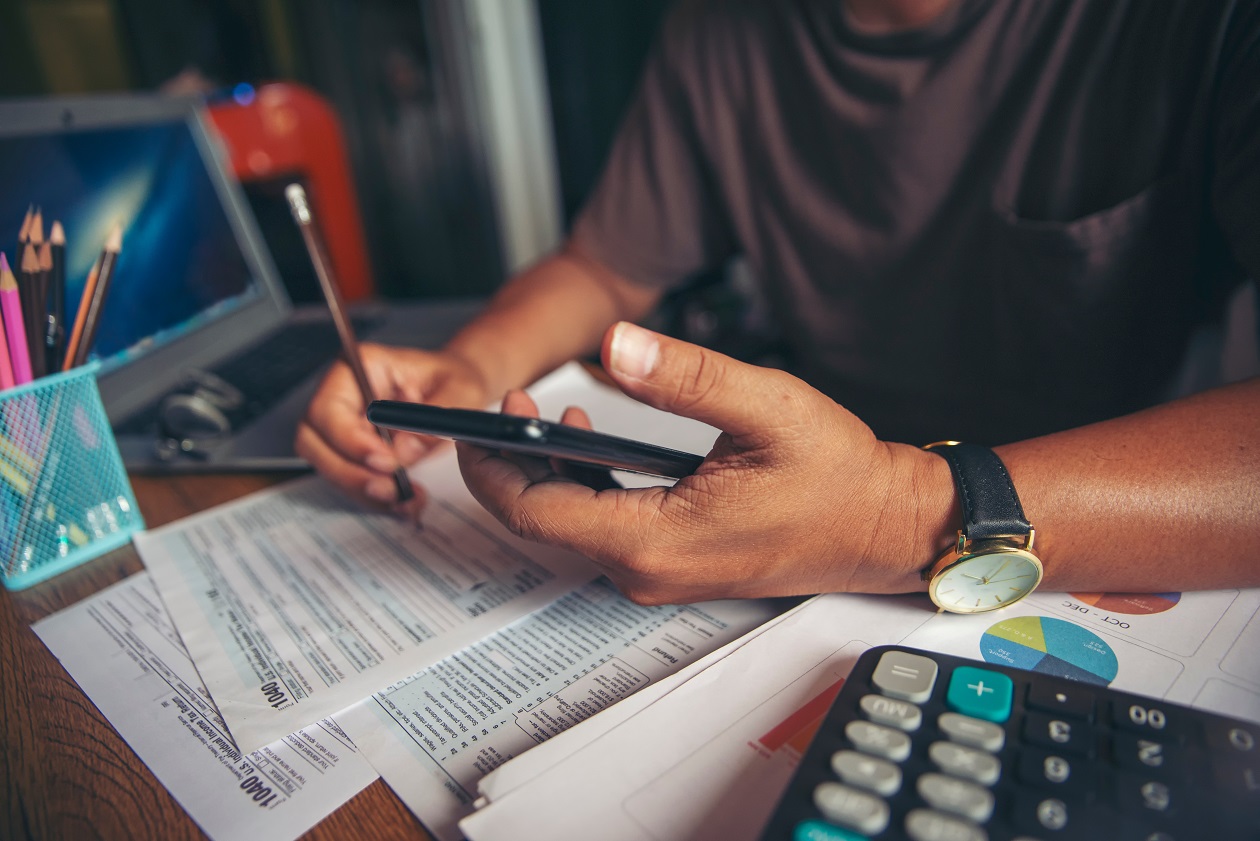 man holding phone working on taxes and paperwork