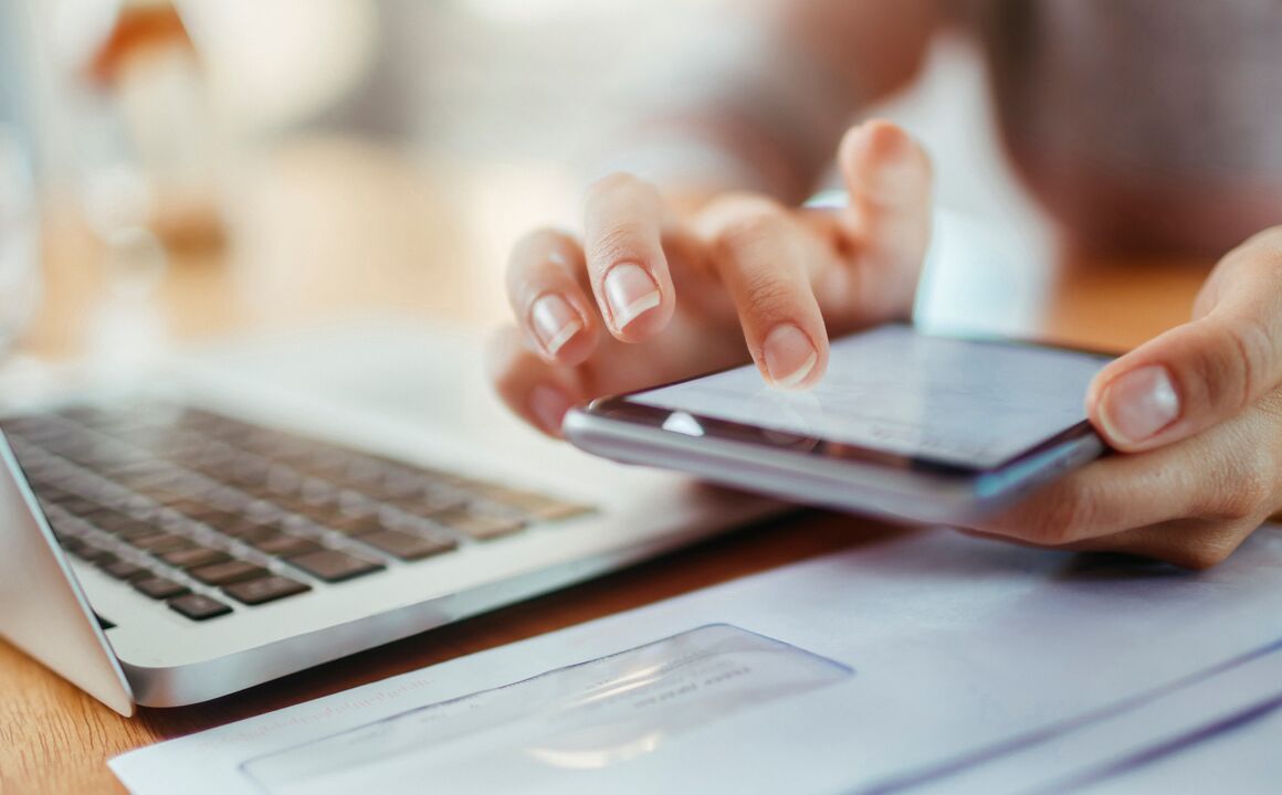 a person using their phone and laptop while sitting