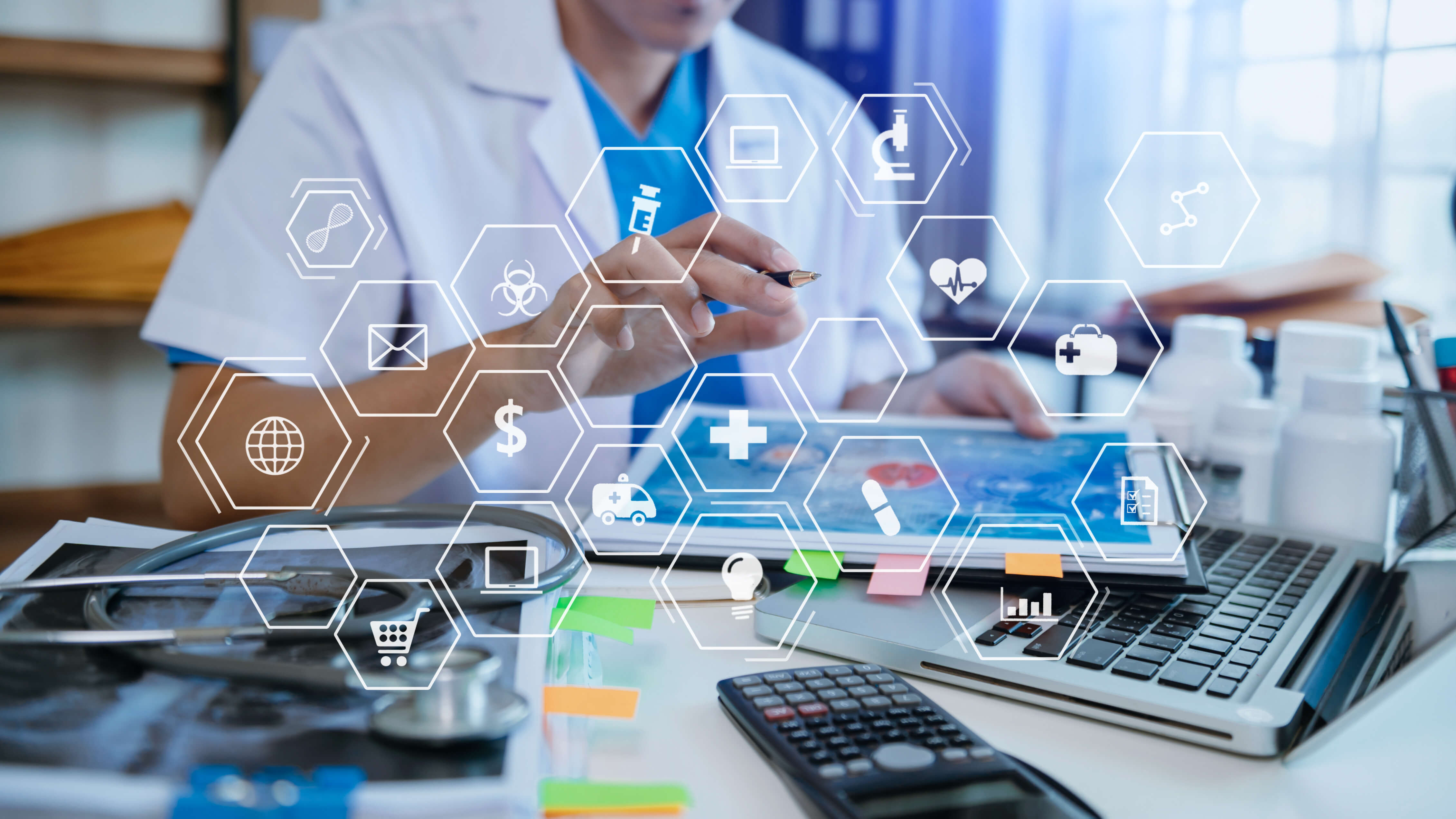 A person in a white lab coat, likely a healthcare professional, interacts with a digital tablet at a desk.