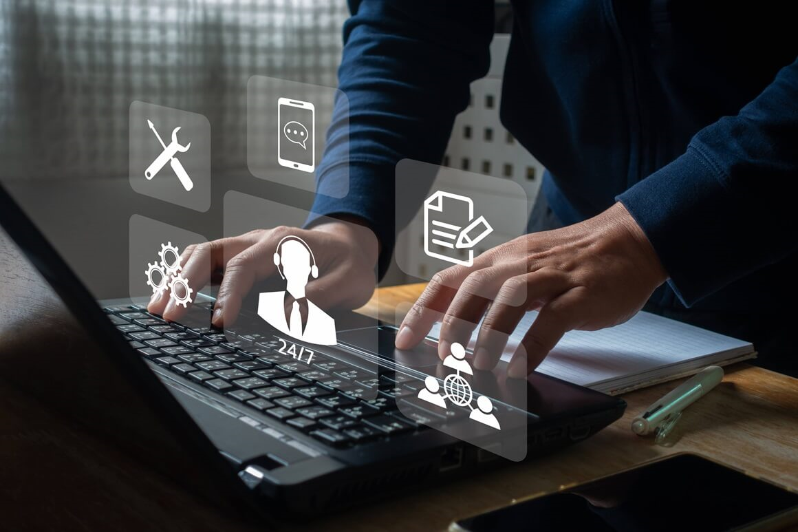 Person typing on laptop with digital customer service icons overlaid, symbolizing technology-driven solutions for service delivery