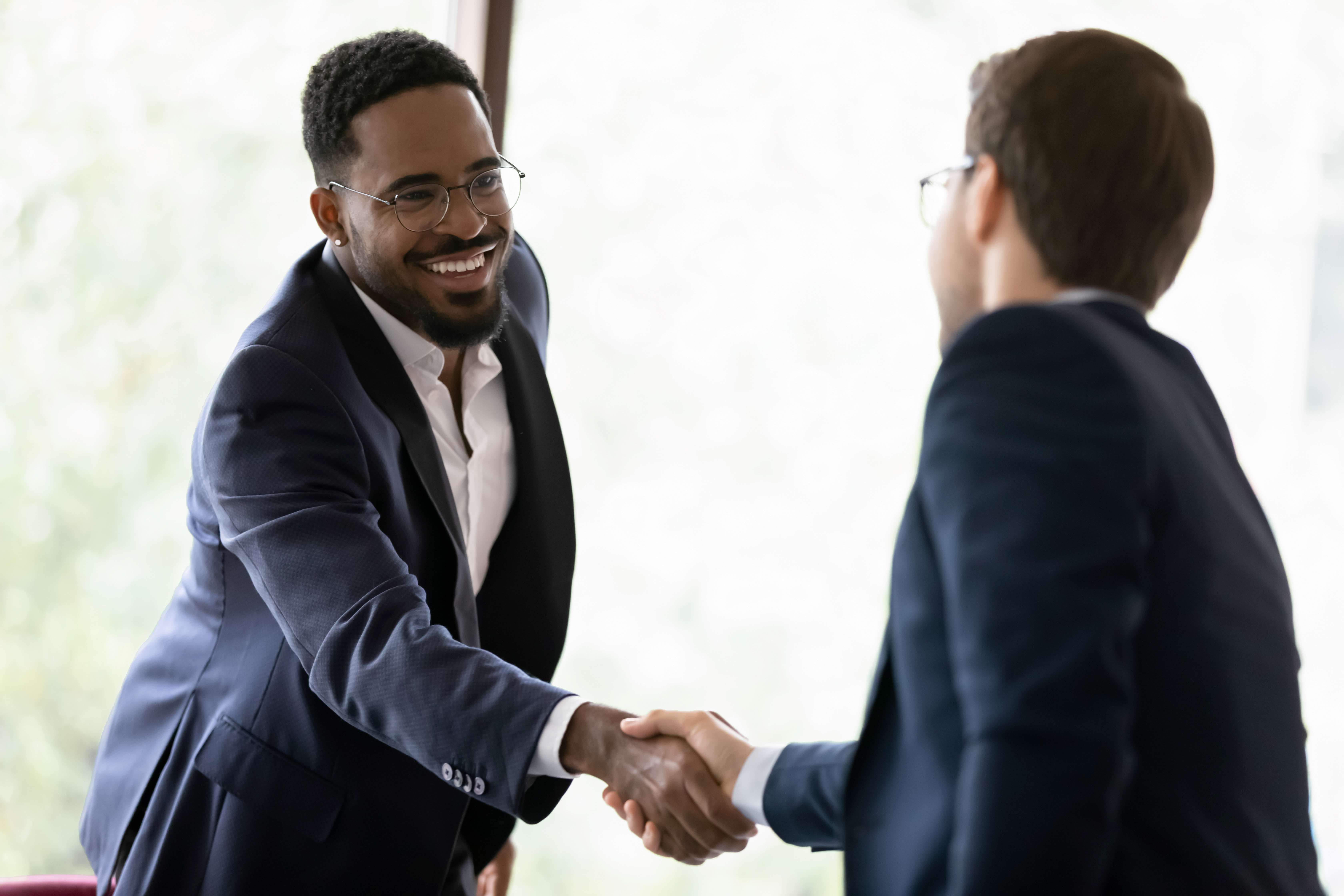 Smiling business partners shake hands in an office setting