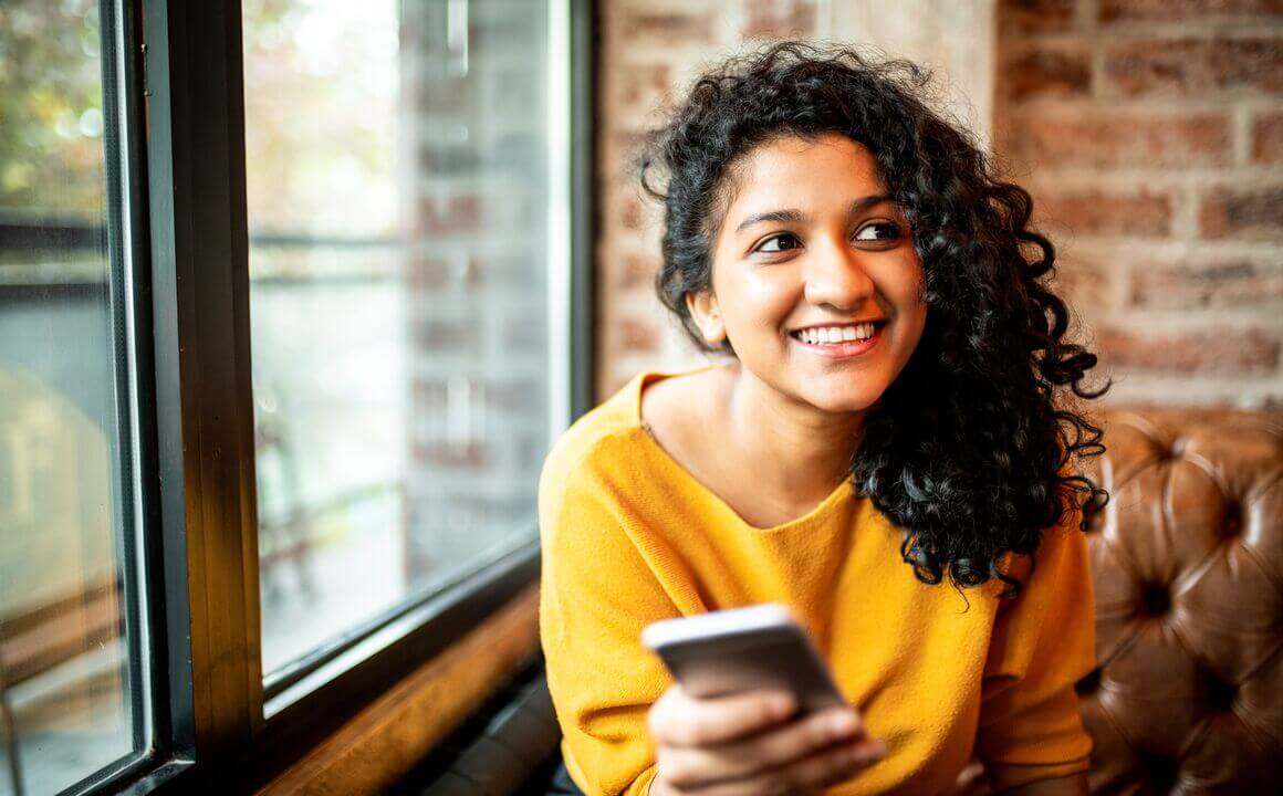 young woman smiling holding cell phone