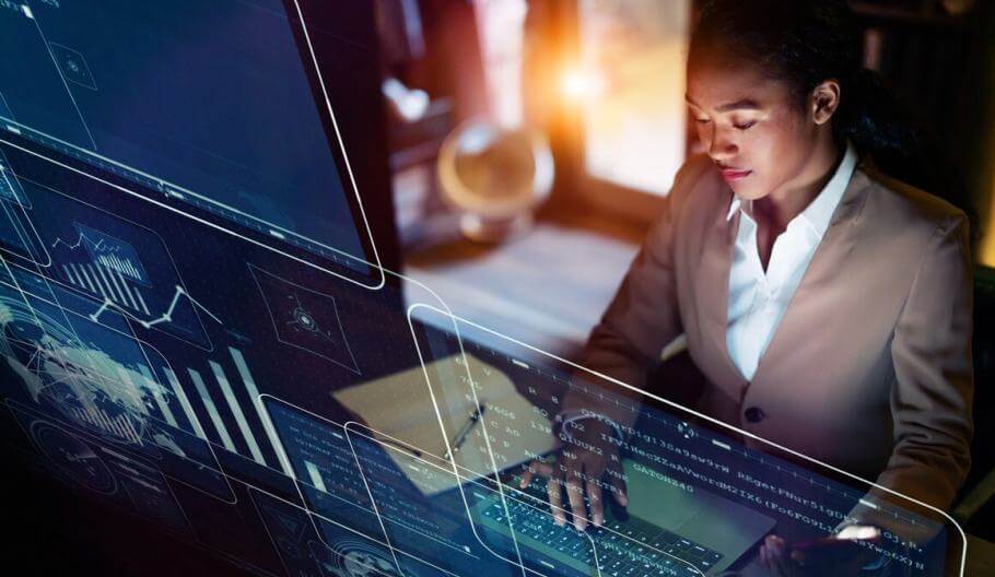 business woman sitting at a desk with computer screens