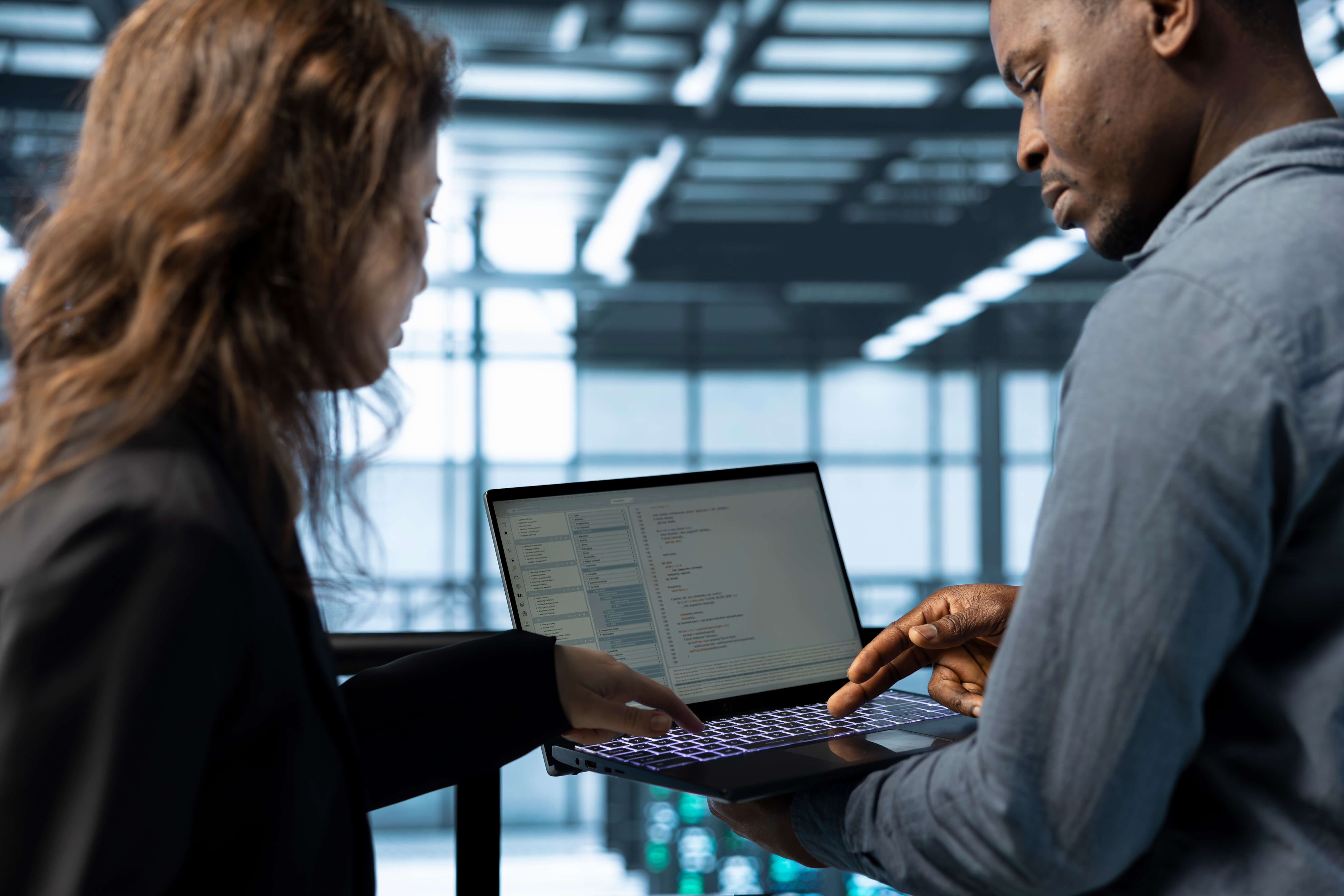 Two individuals collaborating over a laptop 