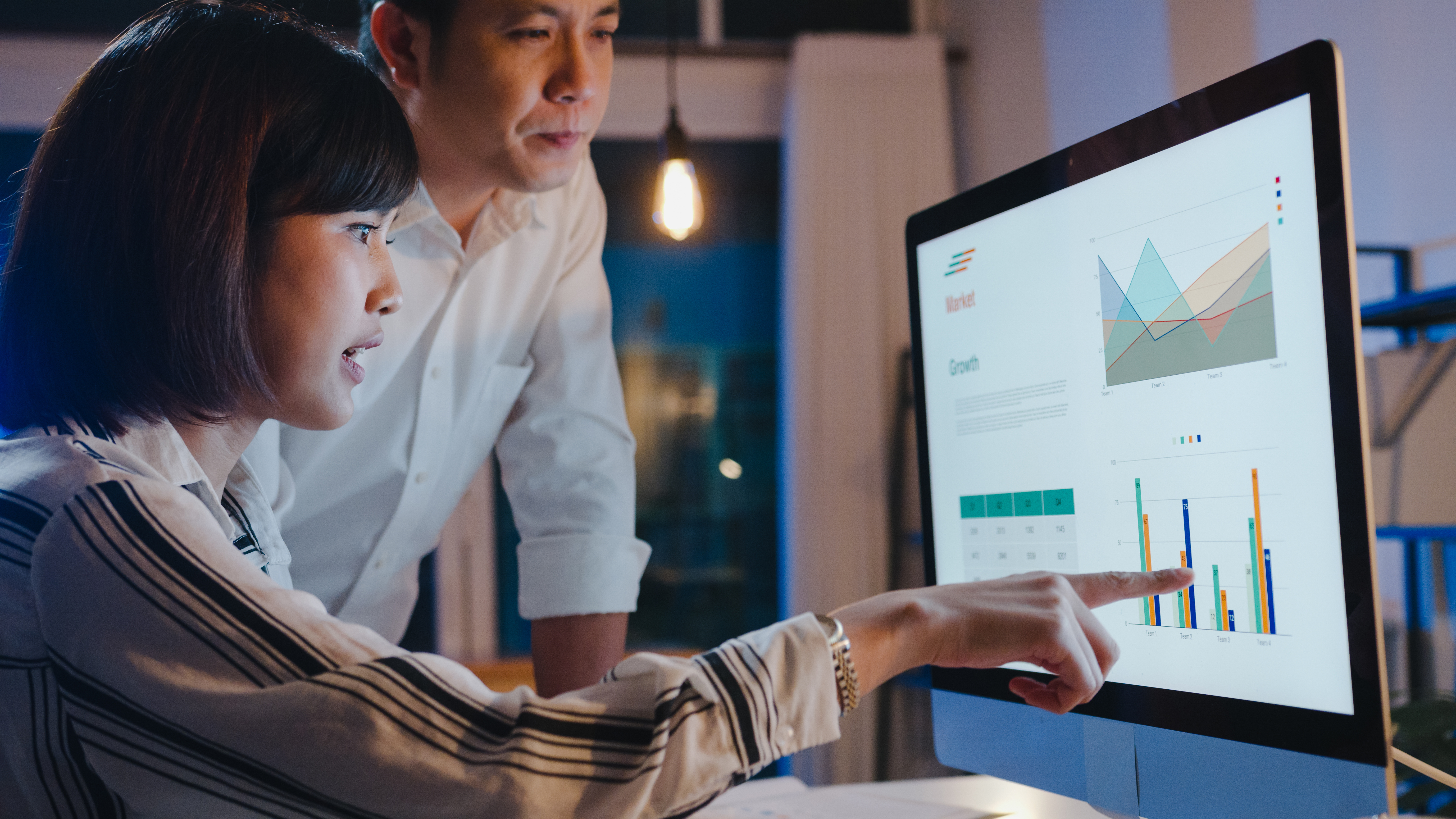 man and woman looking at data on a computer screen