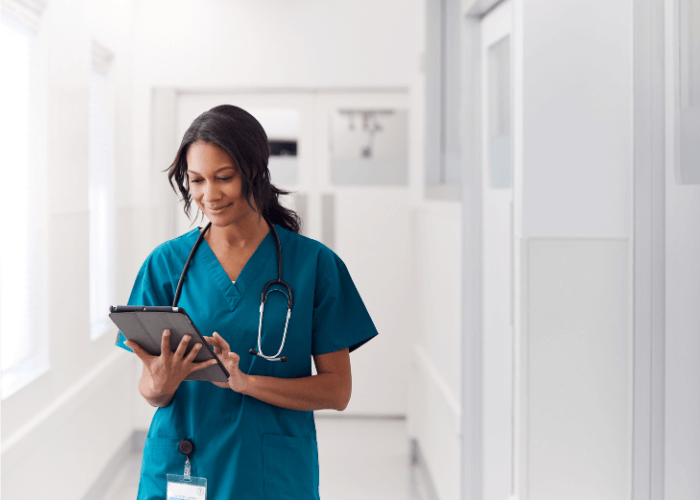 nurse walking down corridor looking at tablet