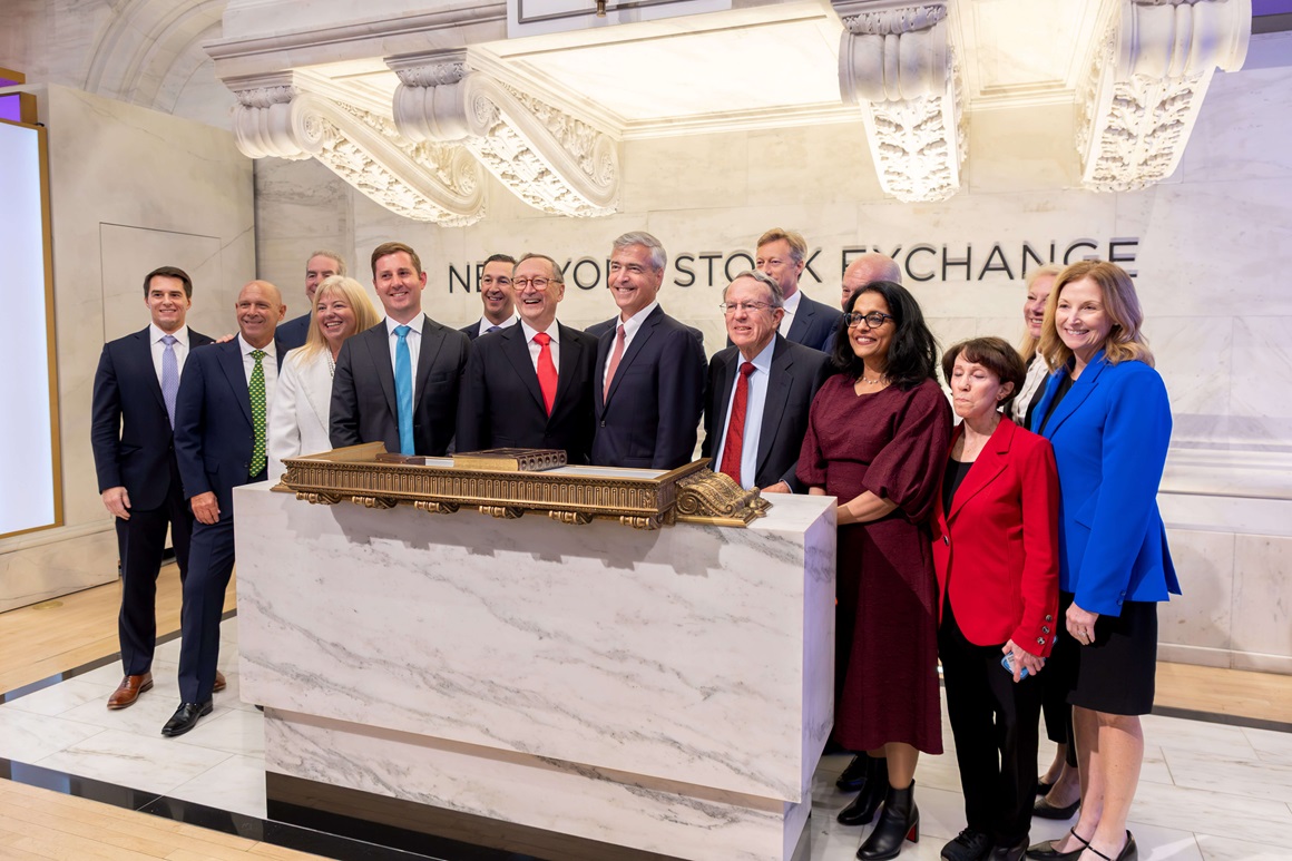 The Maximus executive team and Board of Directors pose in front of the NYSE sign.