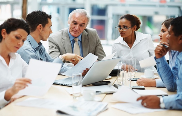 Old white business man leading a business meeting.