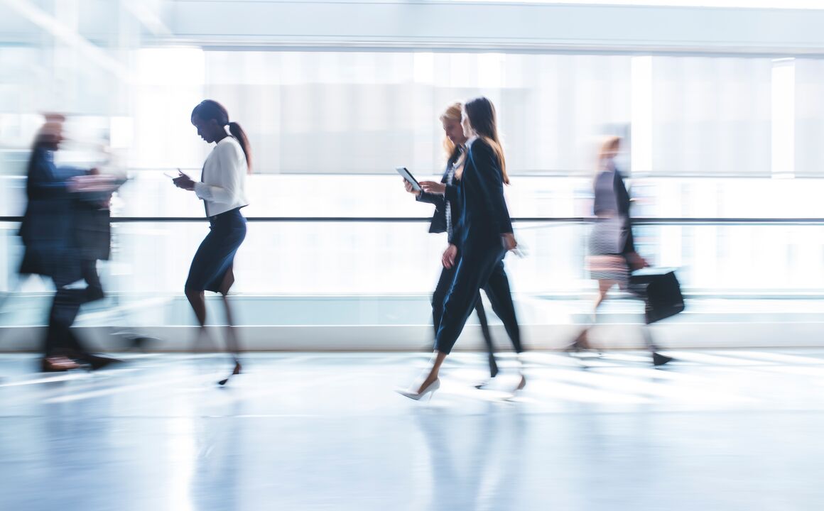 Blurred image showing movement of business professionals walking down an office hallway