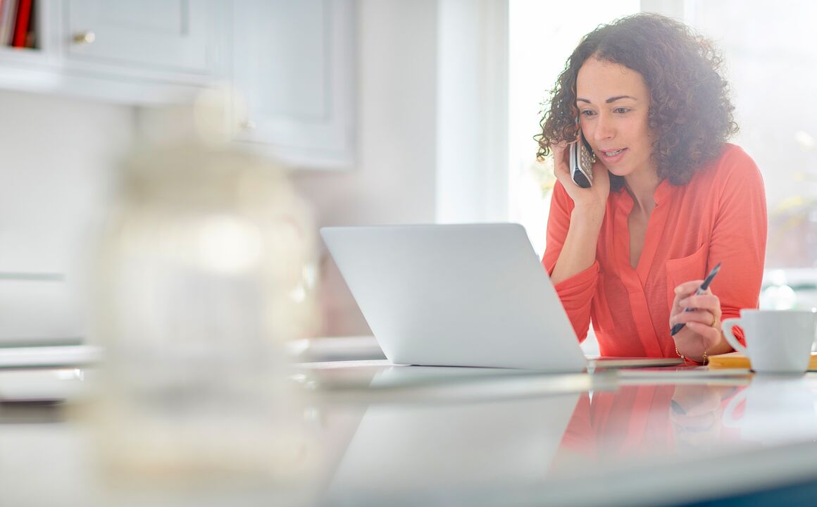 woman talking on phone and looking at laptop.