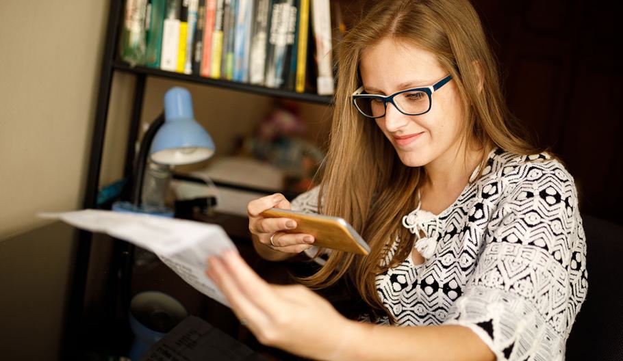 Woman taking a photo of a document with her phone so she can use it to enroll in health insurance