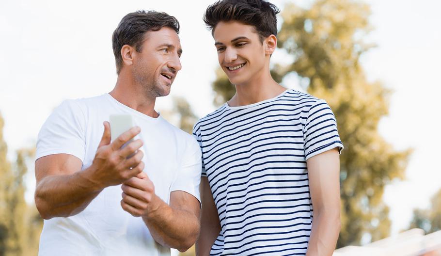 Father and son look at mobile phone showing the results of their paternity establishment order