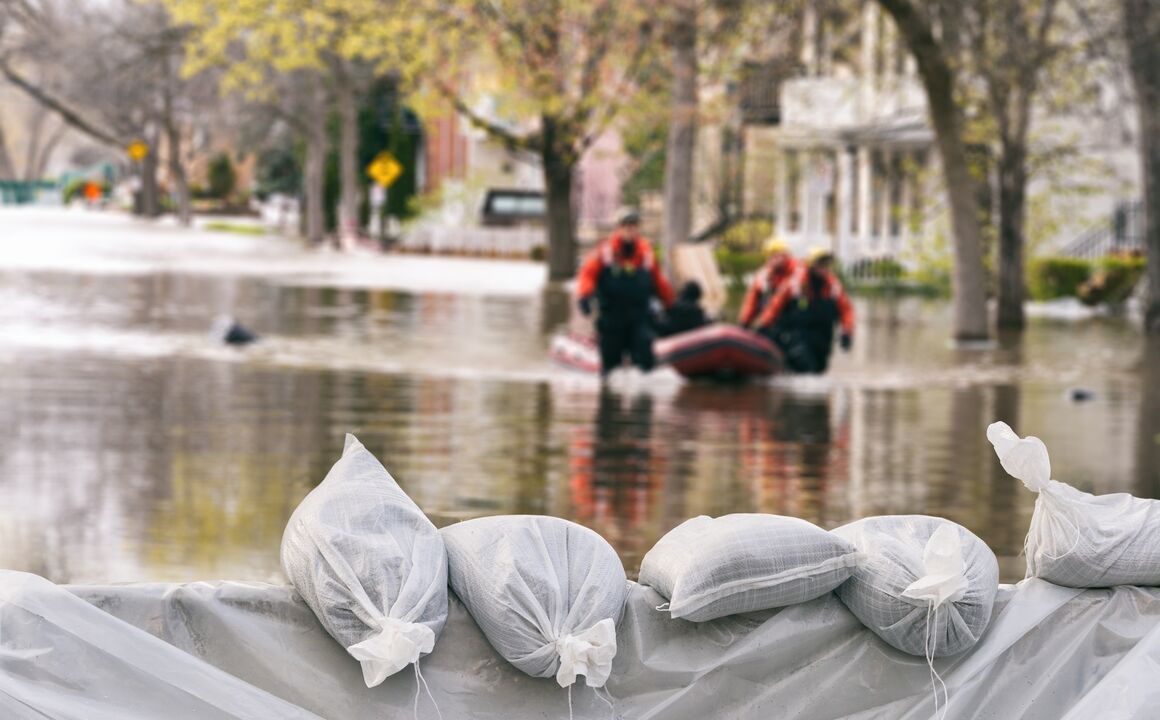 Disaster workers in a flood carrying a raft.