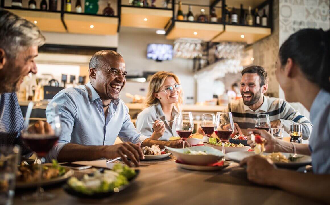 Cheerful business colleagues talking about something funny on a lunch break in a restaurant.