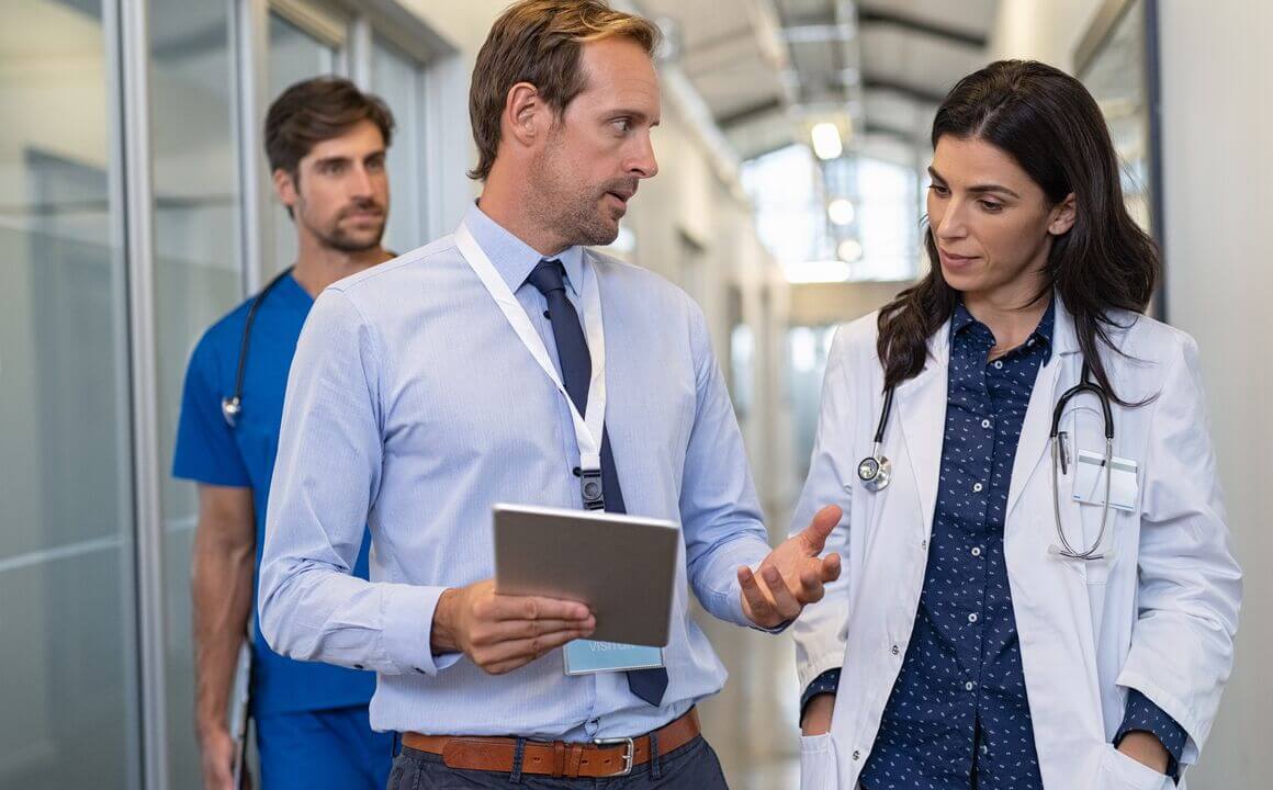 An MCO administrator discusses the credentialing process with a Medicaid provider while walking down a medical center hallway