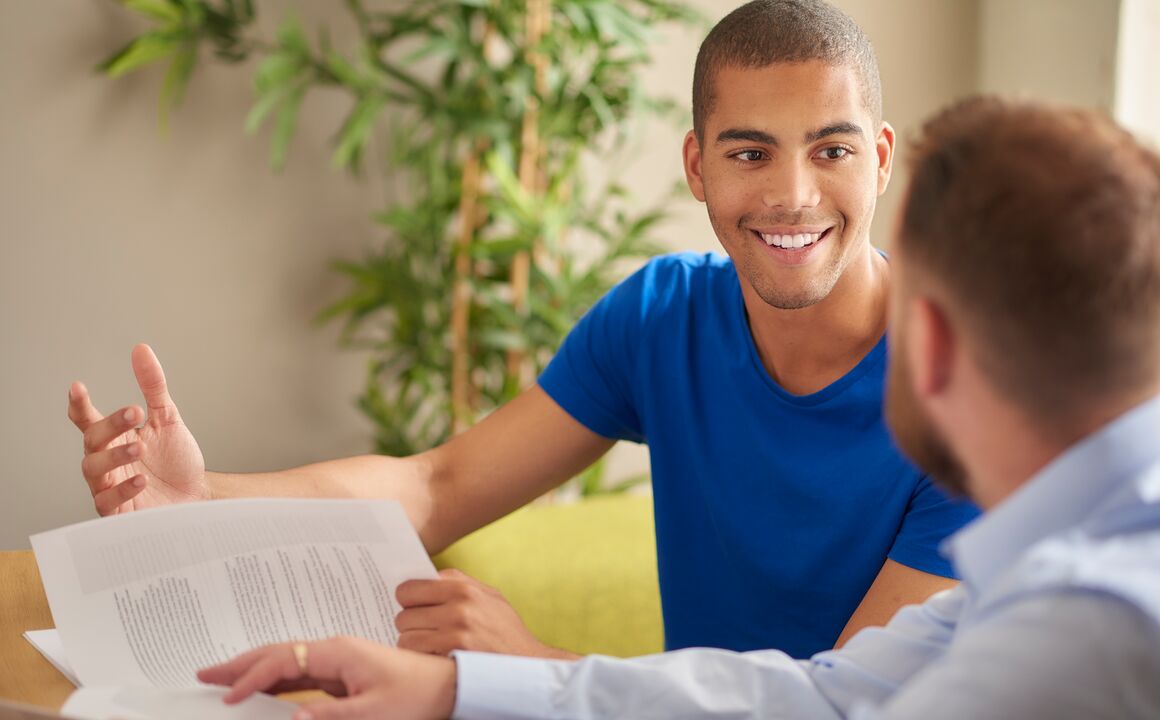 A young man receiving job placement services discusses training opportunities with his employment coach in an office.