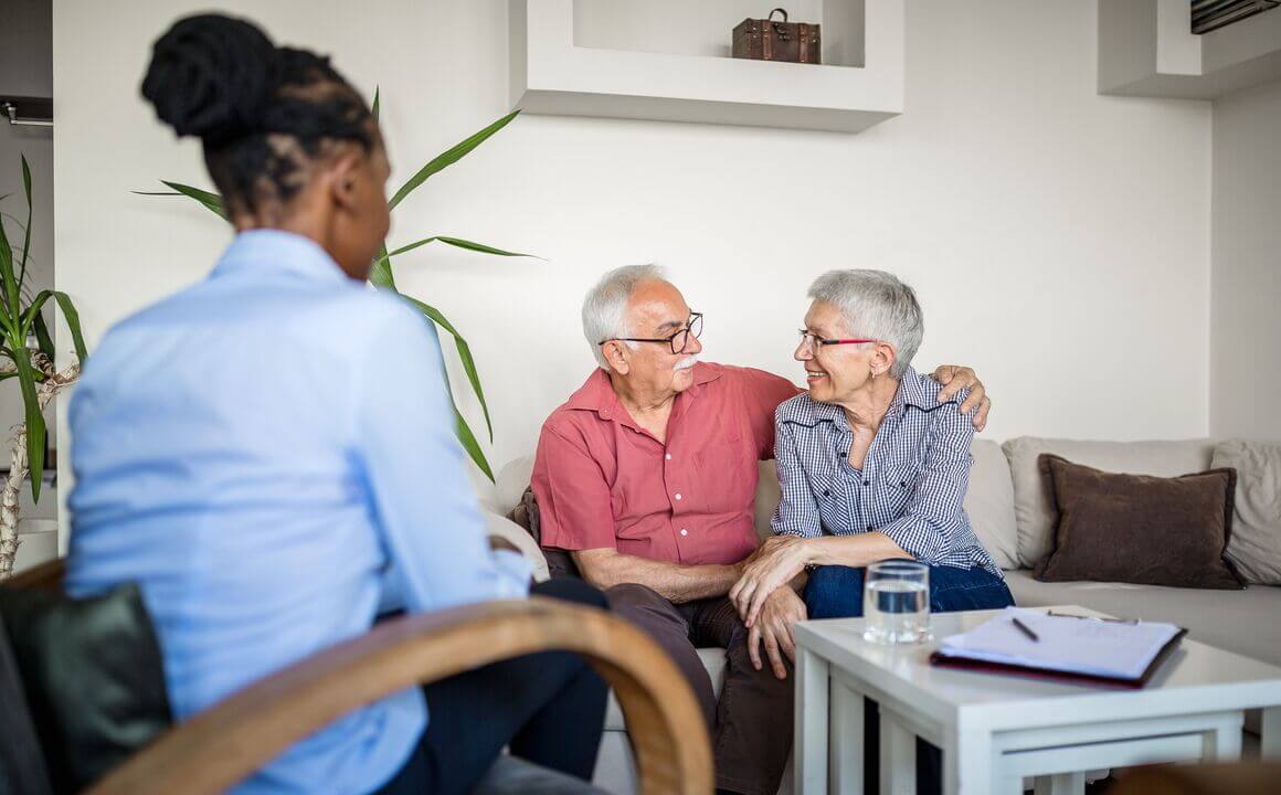 Older couple smiles at each other during a clinical assessment at their home.  