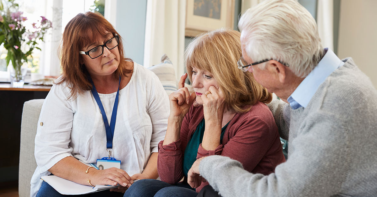 Clinical assessment professional listens to a concerned woman seated next to an older man