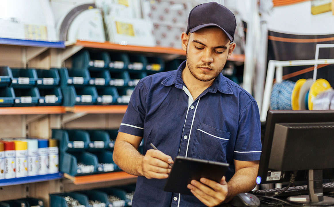 Young man takes inventory on a tablet while working at an auto shop