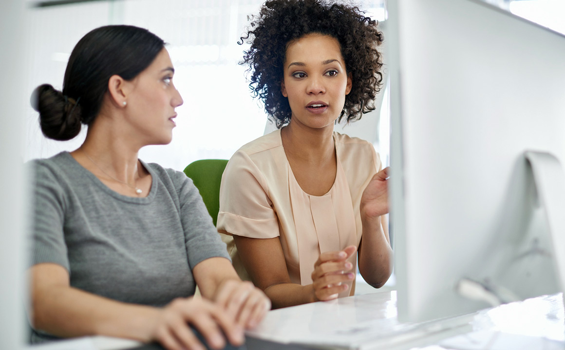 Image of two women talking in from of a computer