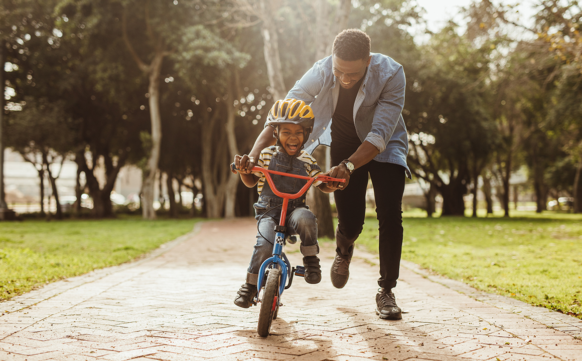 Image of a young boy learning to ride a bike. 