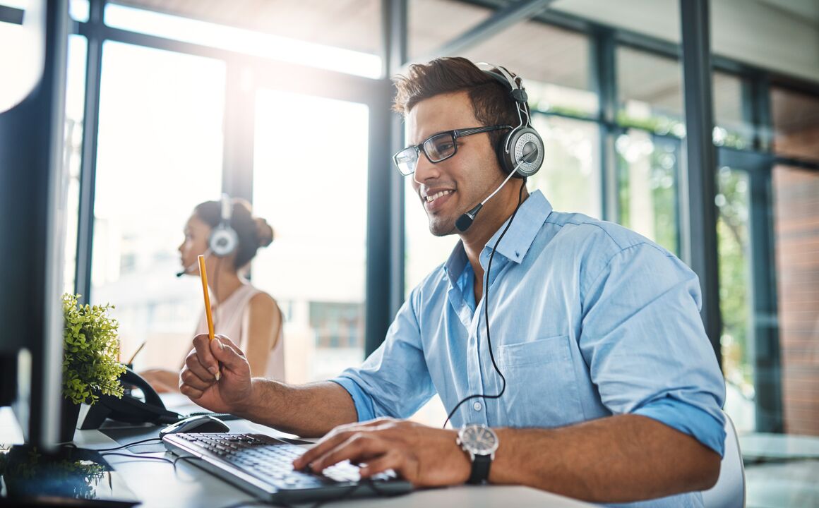 handsome Image of a young man working in a call center with a female colleague in the background