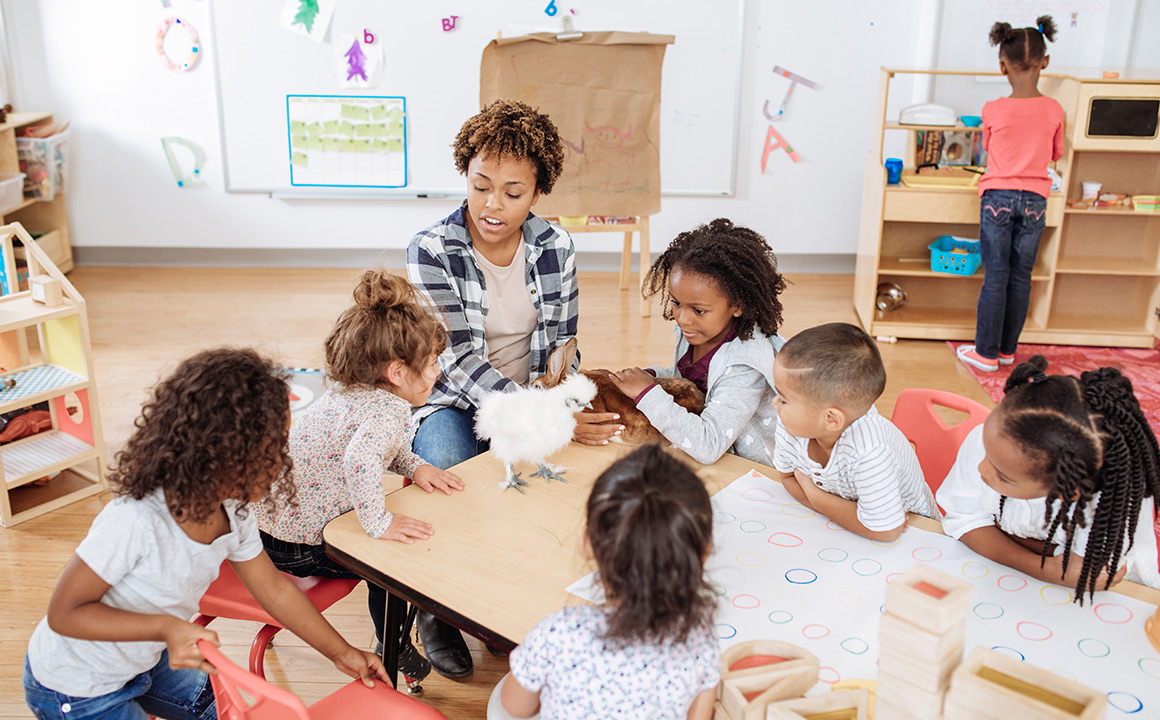 Image of a teacher sitting with kids at a table