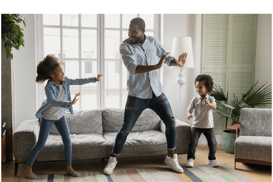 Image of a dad and his kids dancing in the living room