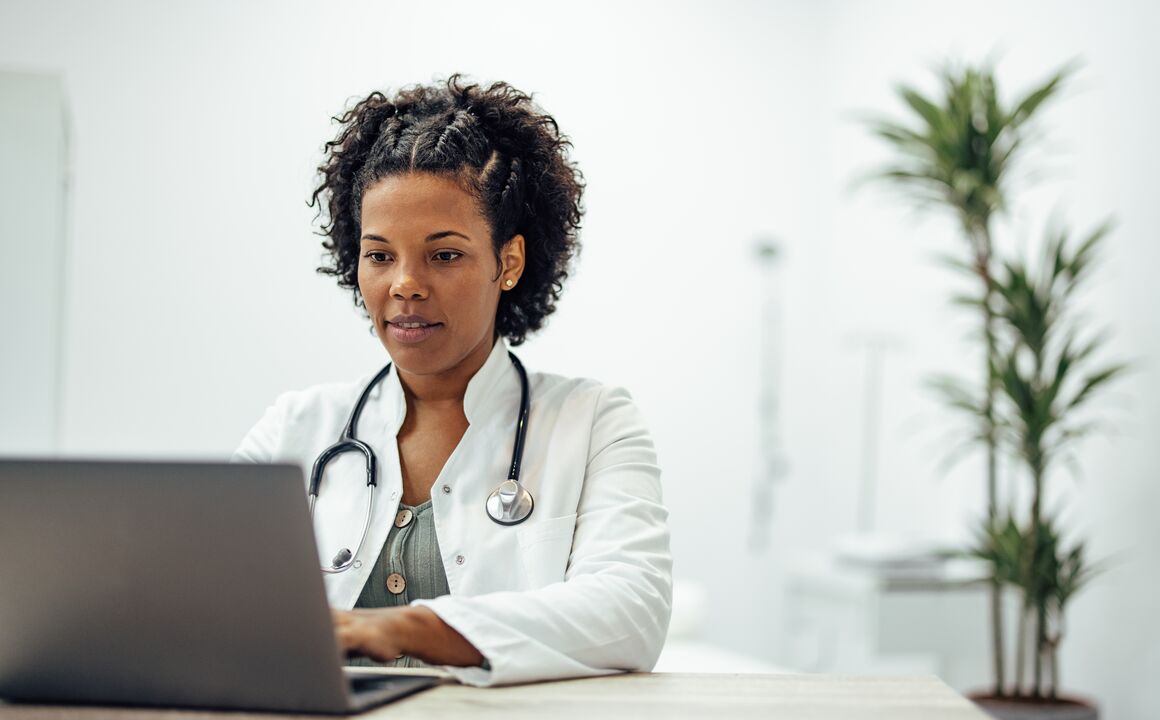 Image of a doctor sitting at a desk looking at a laptop