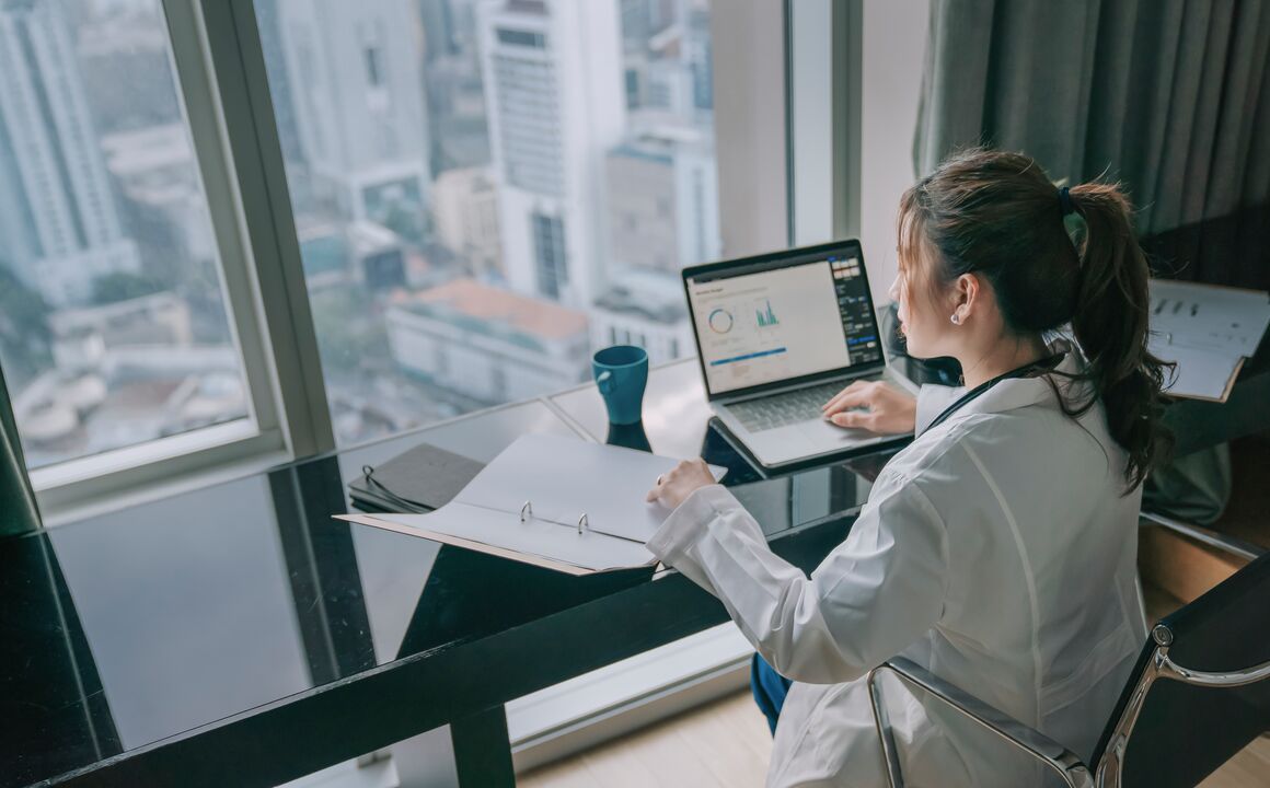 Image of a doctor sitting a desk with a view of the city