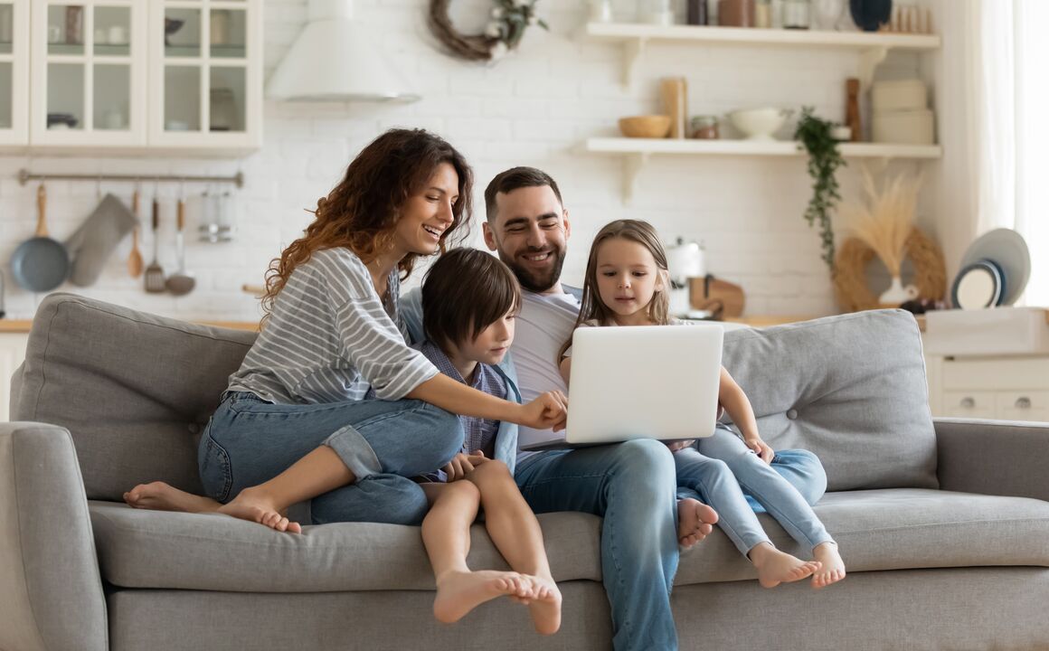 Family sitting on a couch holding a laptop