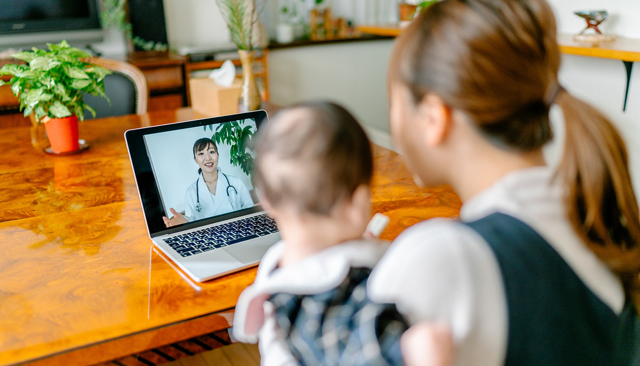 Image of a mother with her baby video calling doctor from home. 