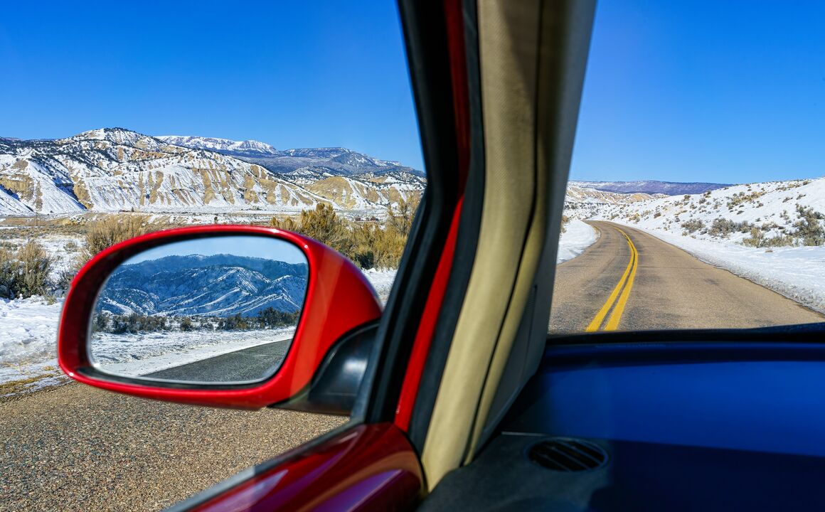 Image of the mountains in the rearview mirror of car