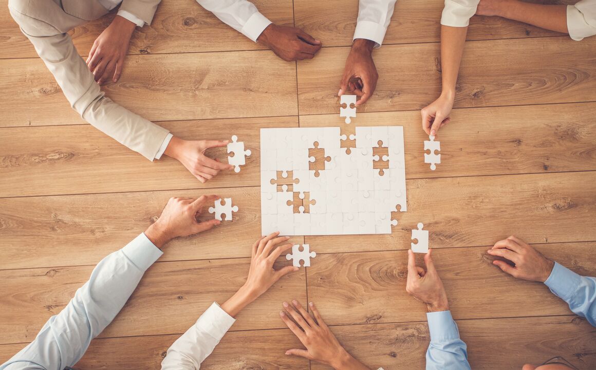 Image of a group of people working on a puzzle toether