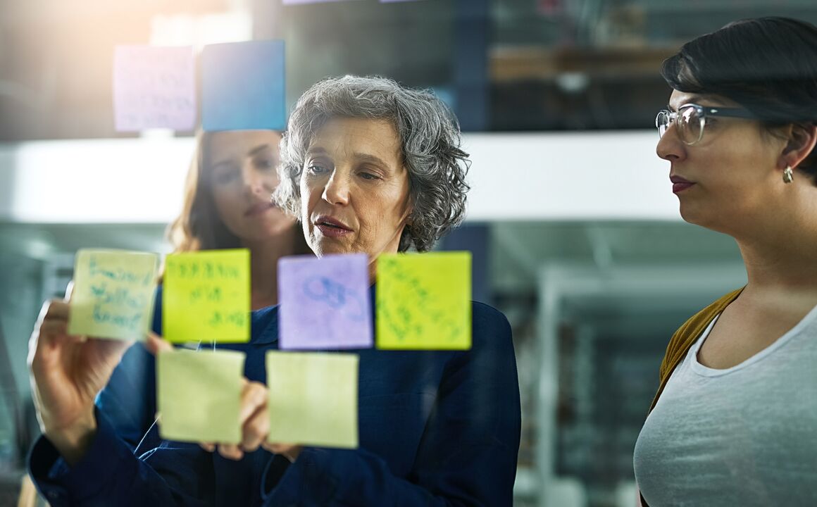 Image of a woman using sticky notes on a board during a team meeting