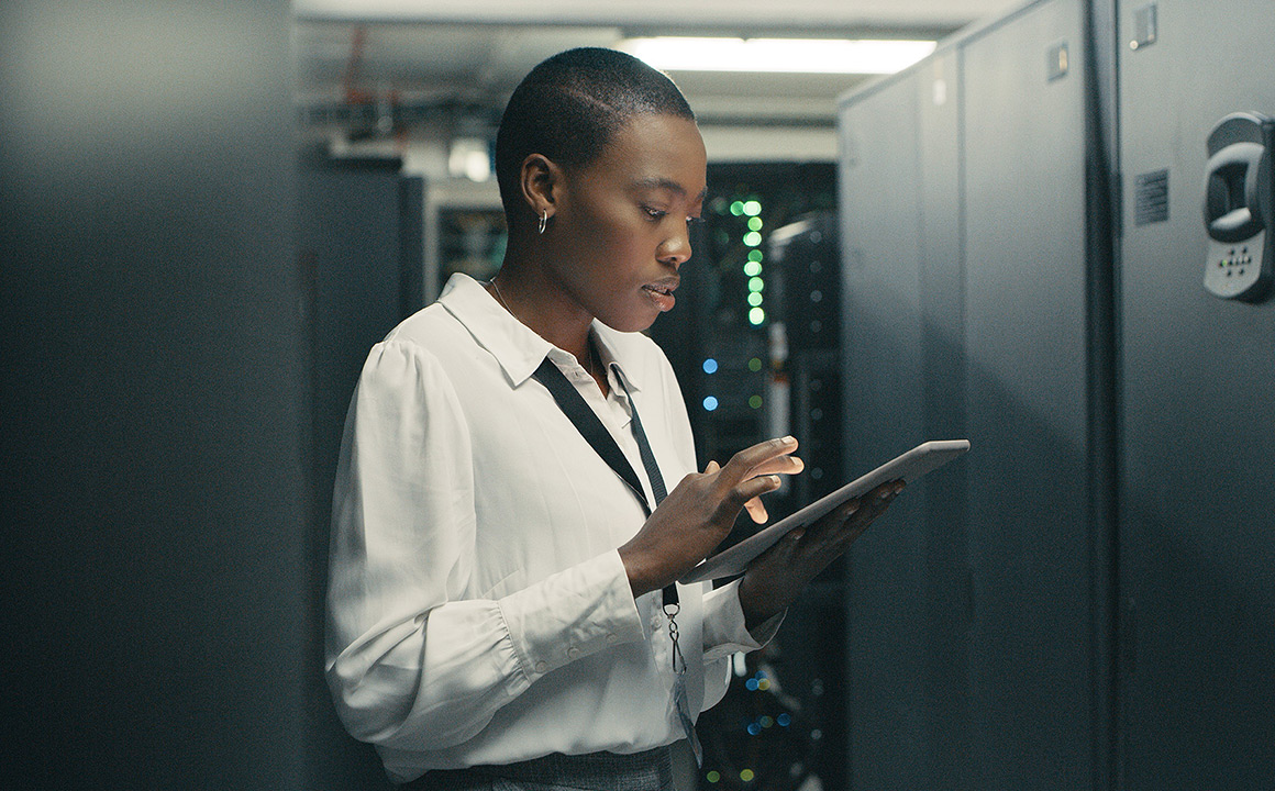 Image of a woman looking at a tablet in a data center