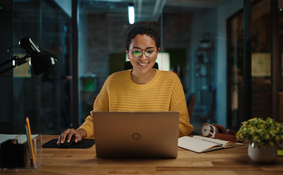 Image of a woman smiling working looking at her laptop screen