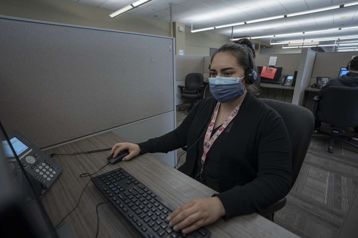 Image of woman wearing a mask in a contact center. 