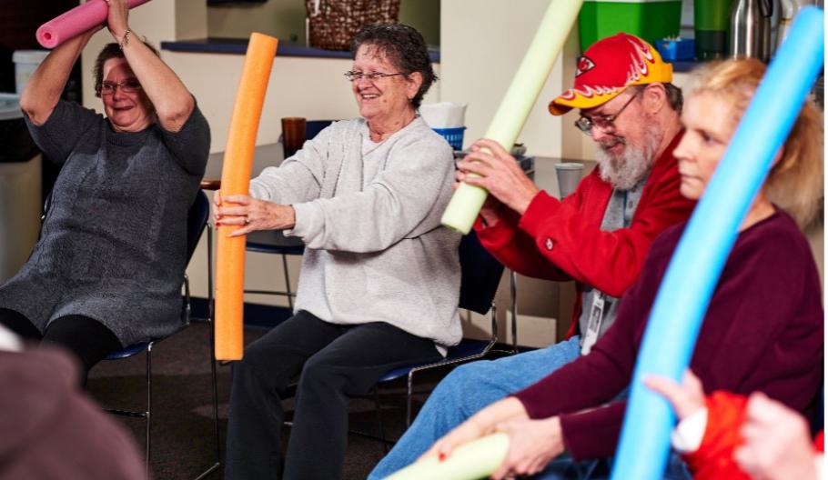 Image of adults at Midland Care doing exercises with pool noodles