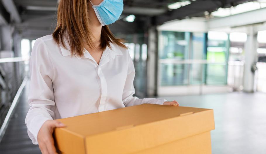 Image of a woman wearing a medical mask carrying a box. 