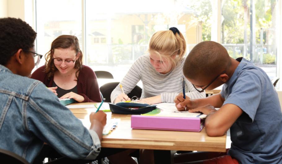 Image of a group of teens writing at a table. 
