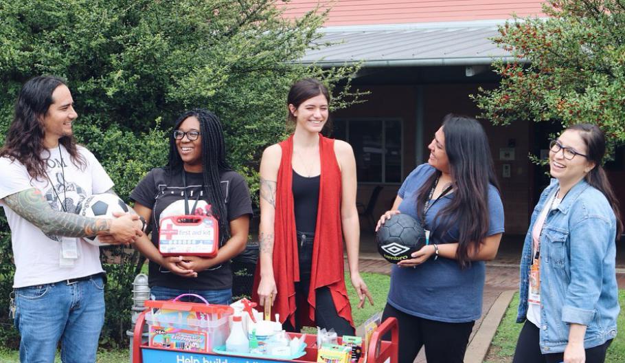 Image of a team of Children’s Advocates standing in front of SAFE’s Family Shelter with a cart of activities to keep children in the shelter engaged and busy.