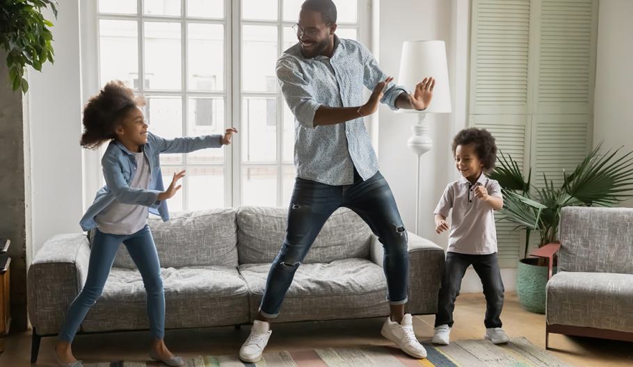 Image of a dad and kids dancing in living room