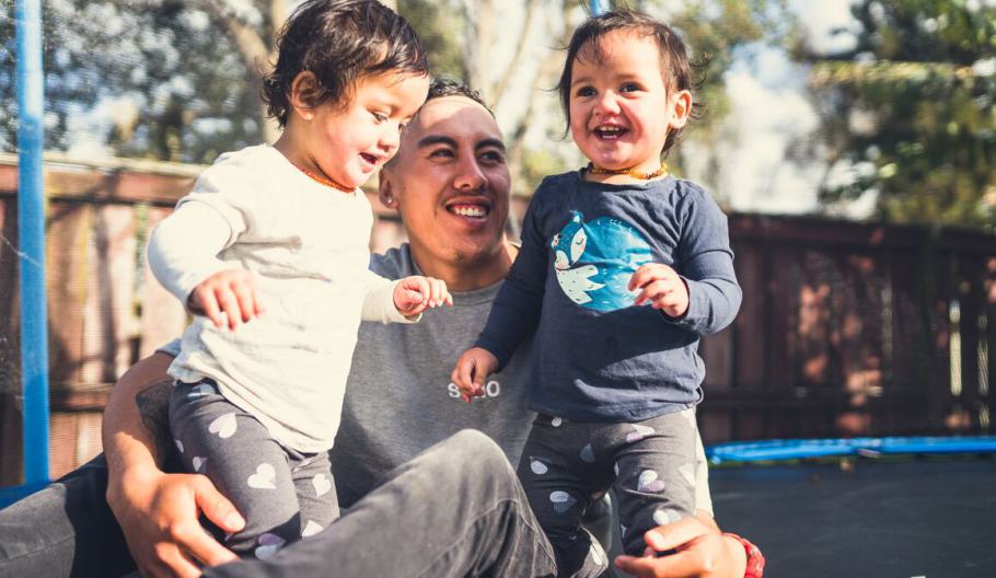 Image of father smiling while playing with his kids