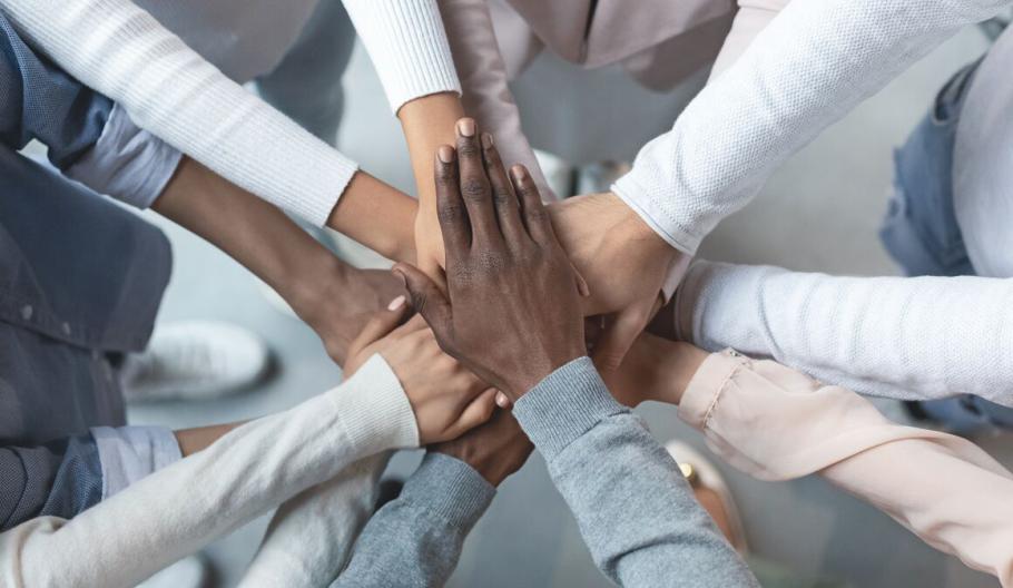 Image of business professional displaying teamwork by having their hands stacked in a circle together