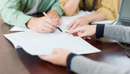 Image of hands signing a contract. 